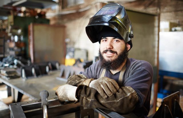happy welder in construction and fabrication steel facility warehouse